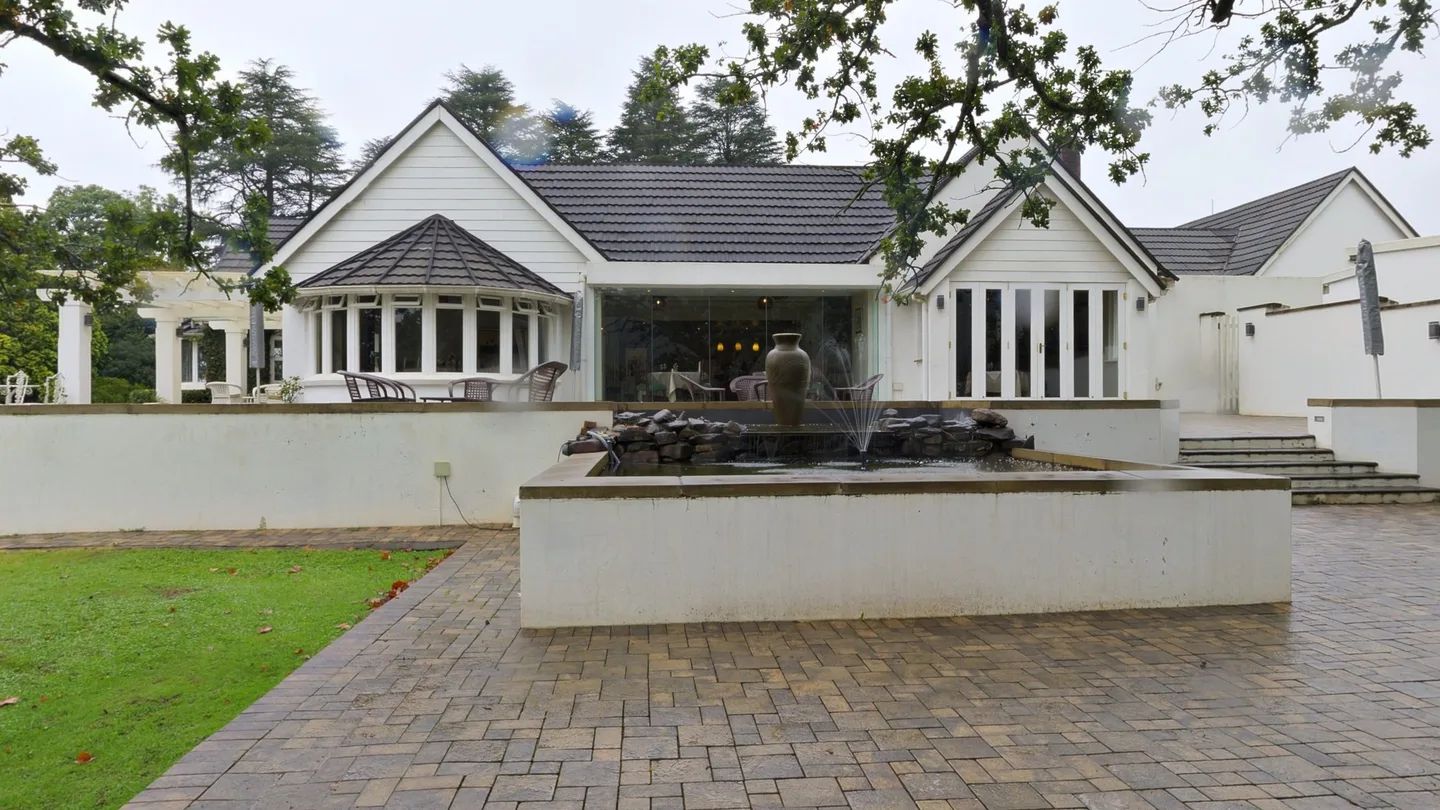 Het terras van de B&B met een fontein, en het huis met glazen deuren erachter.